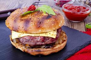 huisgemaakte burger met sesambroodje en rundergehakt op zwarte steen. studio foto