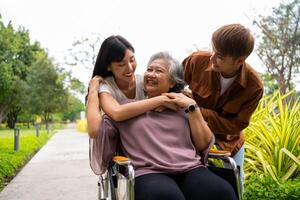 Aziatisch voorzichtig verzorger of verpleegster nemen zorg van de geduldig in een rolstoel. concept van een gelukkig pensioen met zorg van een verzorger en spaargeld en senior Gezondheid verzekering, een gelukkig familie foto