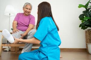 een jong Aziatisch Dames fysiotherapeut verpleging is assisteren een ouderen vrouw oefening uitrekken spieren Bij huis of een premie kliniek voor herstel, concept van fysiek therapie. foto