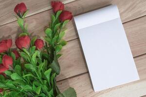 Notitie boek met bloemen Aan houten bureau. direct bovenstaande. vlak leggen. foto