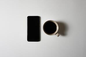 zwart koffie en slim telefoon Aan wit achtergrond. foto