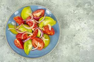 diëet voeding. salade van plakjes verse heldere tomaten en uien. studio foto