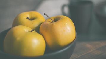 geel appels in een klei bruin bord Aan de tafel foto