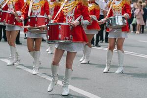 straat prestatie van feestelijk maart van drummers meisjes in rood kostuums Aan stad straat. jong meisjes trommelaar in rood wijnoogst uniform Bij de optocht foto