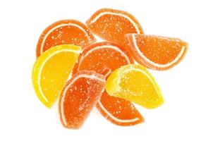 Oranje en gele plakjes zoete fruitmarmelade in suiker geïsoleerd op een witte achtergrond