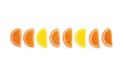 Oranje en gele plakjes zoete fruitmarmelade in suiker geïsoleerd op een witte achtergrond