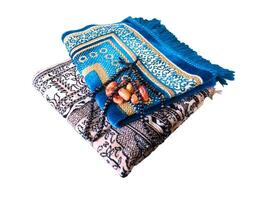 gevouwen moslim gebed mat gebruikt naar betalen met tasbih en khajoor Aan wit achtergrond foto