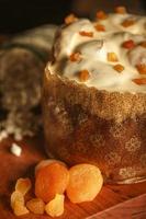 witte chocolade panettone met gedroogde abrikoos op houten tafel met kerstversieringen foto