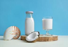een glas en een fles van veganistisch kokosnoot melk Aan de blauw achtergrond foto