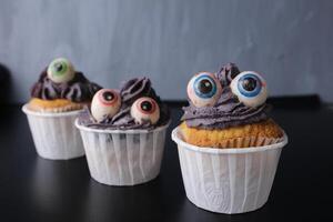 drie cupcakes Aan een zwart achtergrond voor de halloween vakantie. eng en grappig voedsel. snoepgoed voor de vakantie foto