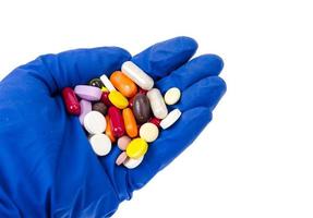 hand in medische handschoen houdt gekleurde pillen, pillen en capsules.