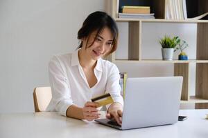 vrouw genieten met online boodschappen doen toepassing en op zoek Bij laptop voor vullen credit kaart aantal naar betaling. foto