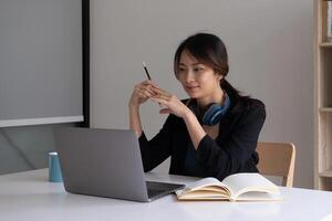een vrouw luistert naar een leerzaam webinar Aan haar laptop terwijl vervelend koptelefoon. foto