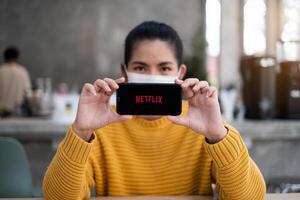 Chiang mei, Thailand apr 14 2021 . hand- Holding appel iphone met Netflix logo Aan een scherm. Netflix is een globaal aanbieder van streaming films en TV serie. foto