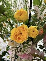 detailopname van een vers boeket met helder geel rozen tussen delicaat wit bloemen en groen gebladerte, perfect voor levendig voorjaar en zomer thema's. foto