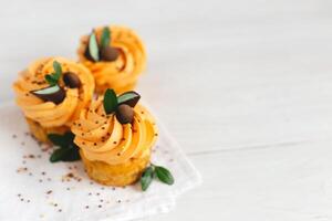 smakelijk pompoen cupcakes met oranje room en decoratie Aan wit houten tafel. foto