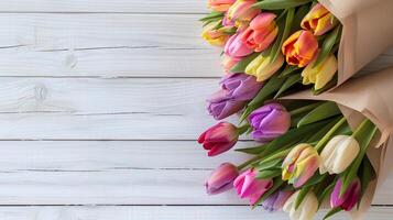 mooi boeketten van veelkleurig tulpen verpakt in een ambacht papier Aan een wit houten tafel. foto