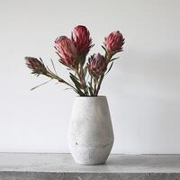 een minimalistische beton vaas houdt een opvallend protea boeket. foto