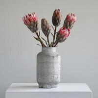een minimalistische beton vaas houdt een opvallend protea boeket. foto