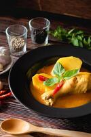 traditioneel Thais geel kerrie met trommelstok kip, vers groente en kruid in kom Aan houten tafel, Thais voedsel concept foto
