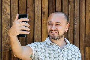 Mens nemen selfie tegen houten muur foto