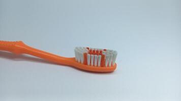een oranje tandenborstel met wit borstelharen Aan een wit oppervlakte foto