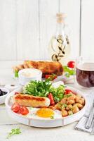 Engels ontbijt. keto ontbijt. gebakken ei, bonen, kip worst en koffie beker. foto