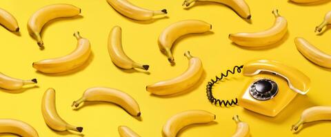 creatief patroon bananen en oud geel telefoon met moeilijk schaduwen patroon Aan geel achtergrond vlak leggen banaan telefoon horizontaal banier foto