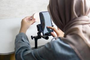 vrouw met hijab voorbereidingen treffen de opname mobiel telefoon naar maken een en produceren inhoud foto