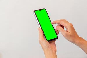 Dames hand- Holding slim mobiel telefoon met blanco groen scherm Aan geïsoleerd wit achtergrond foto