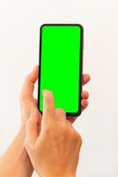 Dames hand- Holding slim mobiel telefoon met blanco groen scherm Aan geïsoleerd wit achtergrond foto