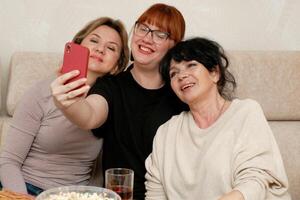 drie lachend Dames nemen een selfie naar de telefoon foto