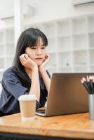 jong zakenvrouw met een beugel looks Bij haar laptop scherm, mogelijk probleemoplossing of diep in gedachte. foto