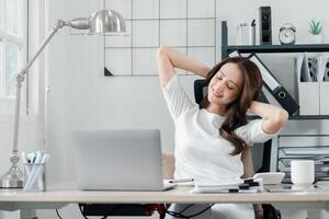 ontspannen professioneel vrouw duurt een breken naar rekken Bij haar werkstation, signalering een moment van welverdiend rust uit in haar bezig dag. foto