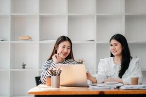 glimlachen professionals verloofd in een samenwerkend discussie met een laptop, sharing ideeën in een modern kantoor ruimte. foto