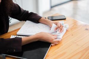 detailopname van een zakenvrouw handen net zo ze minutieus organiseert financieel documenten en grafieken Aan haar kantoor bureau. foto