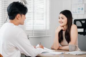 jong vrouw aandachtig luistert terwijl een Mens duurt notities, beide diep betrokken in een huis kantoor discussie. foto