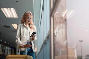 een vrouw Aziatisch wandelen in een luchthaven. mobiel, koffer en reizen met een jong vrouw Aan een reis voor werk of reizen foto