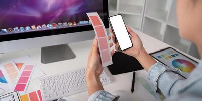 vrouw handen Holding een smartphone wit scherm mockup over- modern grafisch ontwerper kantoor bureau foto