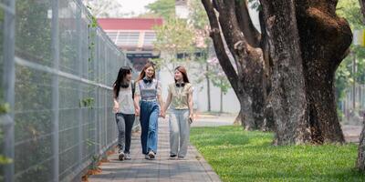 college vrienden wandelen naar klasse samen. Universiteit leerling in campus praten en hebben pret buitenshuis foto