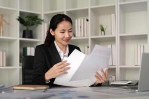 jong bedrijf vrouw Aziatisch of werknemer accounting boekhouding documenten controle financieel gegevens of afzet verslag doen van werken in kantoor met laptop. papierwerk beheer foto