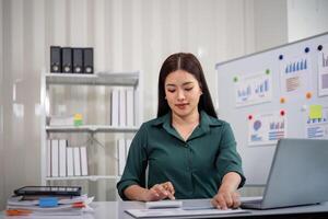 zakenvrouw accountant gebruik makend van rekenmachine en laptop voor financieel gegevens besparing in kantoor kamer, bedrijf financieel, belasting, accounting concept foto