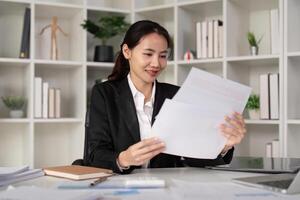 jong bedrijf vrouw Aziatisch of werknemer accounting boekhouding documenten controle financieel gegevens of afzet verslag doen van werken in kantoor met laptop. papierwerk beheer foto