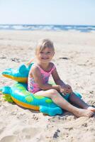 gelukkig meisje van Europese uiterlijk leeftijd van 5 zittend en lachend Aan een opblaasbaar krokodil speelgoed- Bij de strand zomer zonnig dag.familie zomer roeping concept. verticaal foto. foto