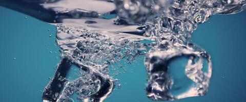 water spatten en ijs kubus. ijs spatten in een glas van water. onderwater- gieten ijs kubussen vallend in Doorzichtig gieter achtergrond. verfrissend kilte drinken. ijs in een glas met blauw achtergrond foto