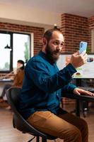 zakenman zit aan bureau met smartphone die e-mail leest met een vriend op afstand foto