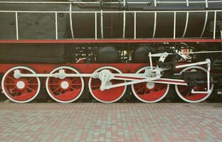 wielen van de oud zwart stoom- locomotief van Sovjet keer. de kant van de locomotief met elementen van de roterend technologie van oud treinen foto