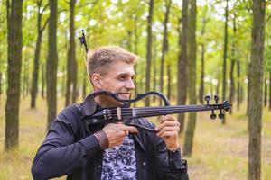 jong mannetje speelt op de viool in het zomerpark foto