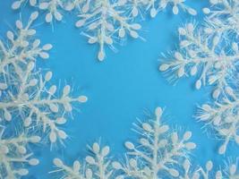 witte plastic sneeuwvlokken met iriserend klatergoud op een blauwe achtergrond. plaats voor inscriptie foto