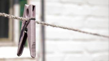 plastic wasknijpers hangen in een rij aan het touw. touw buitenshuis, op een onscherpe achtergrond in een zonnige tuin. waslijn op straat. wasknijpers. foto